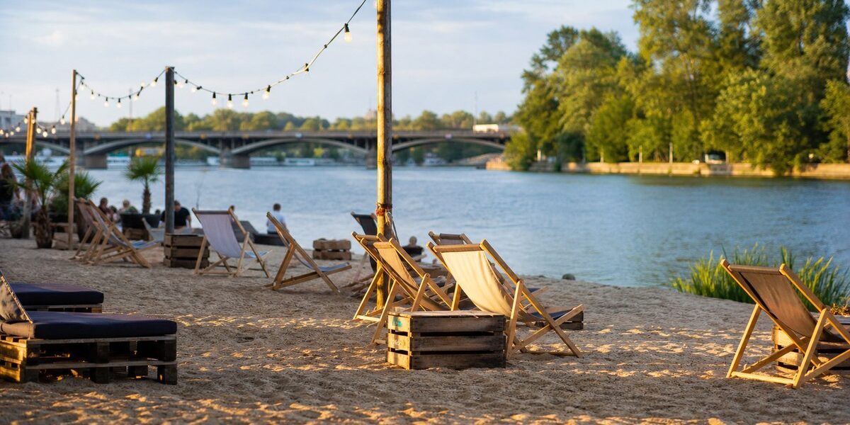 Miejska plaża nad Wartą w Poznaniu z leżakami, drewnianym pomostem i rzeką w tle