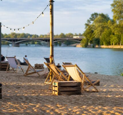 Miejska plaża nad Wartą w Poznaniu z leżakami, drewnianym pomostem i rzeką w tle