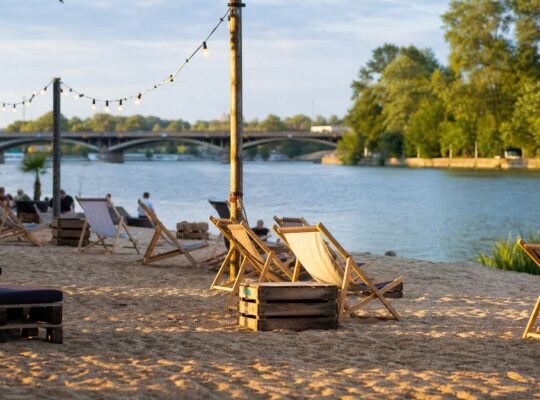 Miejska plaża nad Wartą w Poznaniu z leżakami, drewnianym pomostem i rzeką w tle