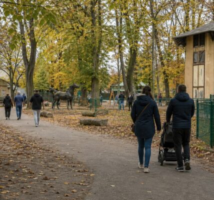 Alejka Starego ZOO w Poznaniu jesienią, po lewej zabytkowa woliera, w tle stare drzewa i spacerowicze